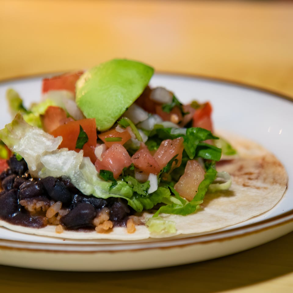 A La Costa Mexican cantina taco with black beans, rice, lettuce, tomato, onion, and avocado.