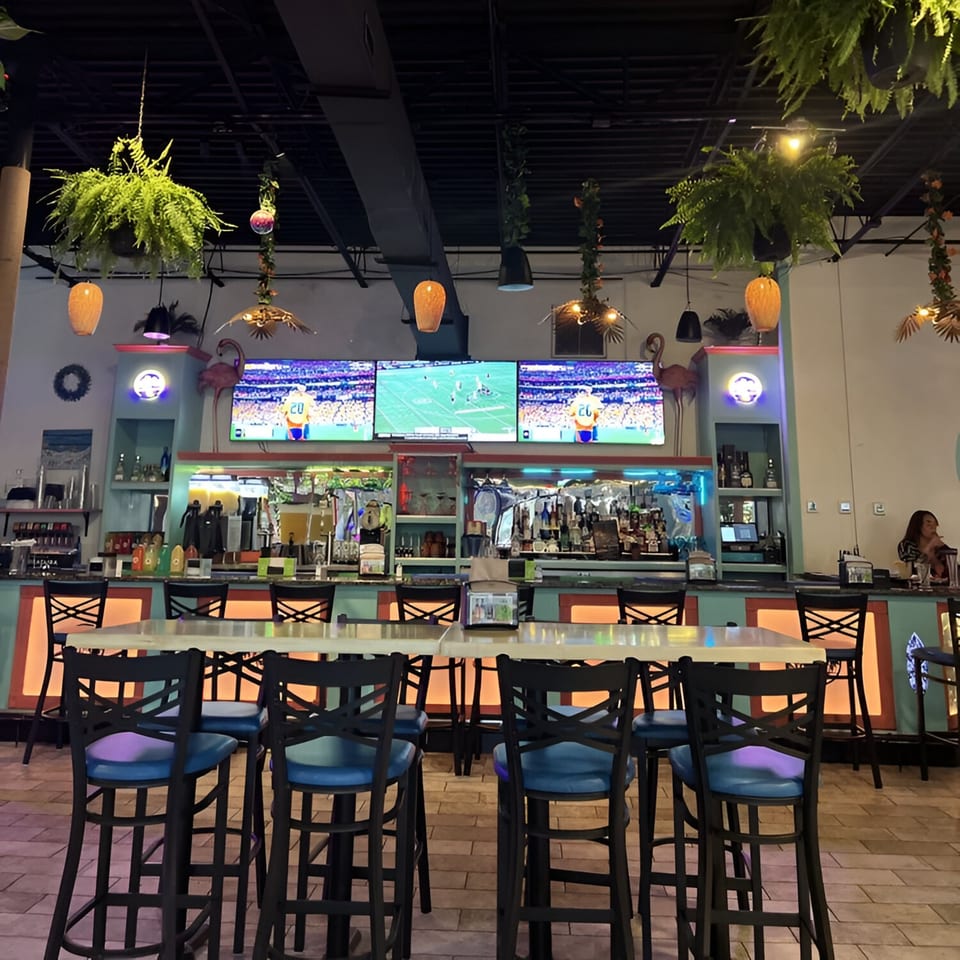La Costa Mexican cantina bar area with three TVs showing sports, high-top tables, and blue-seated stools.